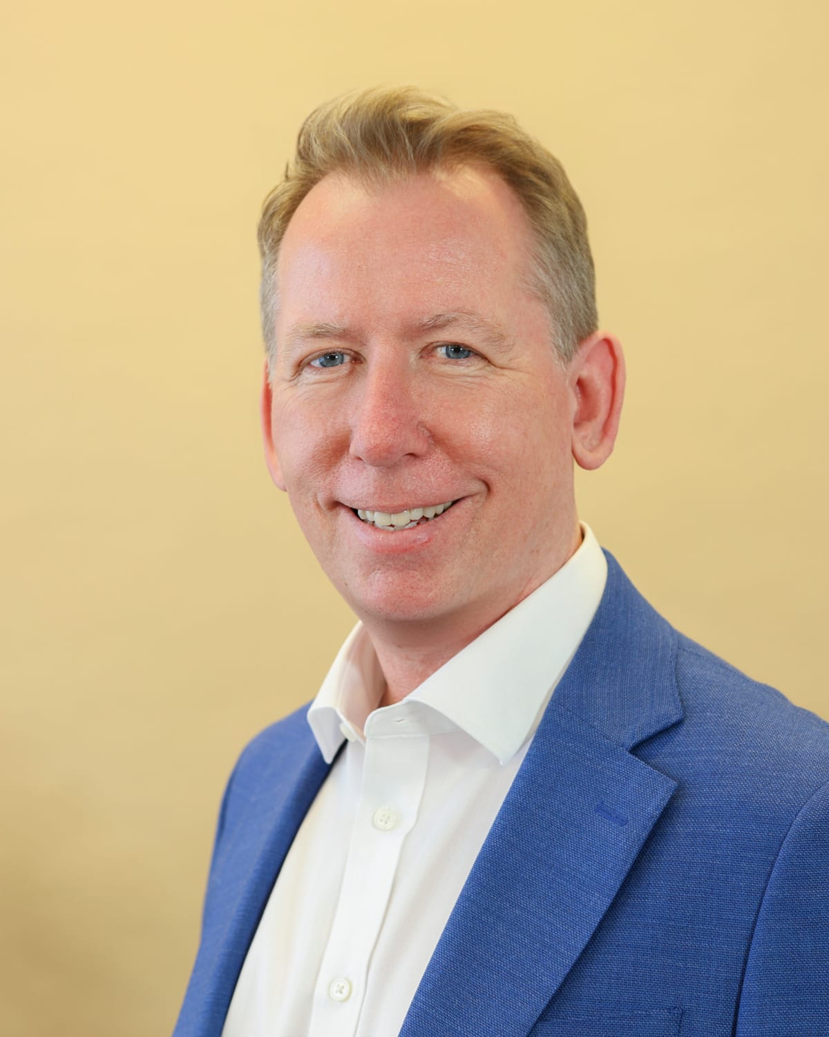 John Margerison, author of The AI Manager, in a blue jacket, smiling at the camera